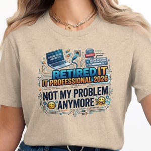May include: Beige t-shirt with a colorful graphic. The graphic includes a laptop, keyboard, and the text "RETIRED IT PROFESSIONAL 2026 NOT MY PROBLEM ANYMORE". The design has a circuit board theme with binary code and smiling emojis.