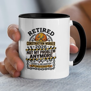May include: White ceramic mug with a black interior and handle. The mug features the text "RETIRED CONSTRUCTION WORKER 2026 NOT MY PROBLEM ANYMORE" in black and yellow, with construction-themed graphics.