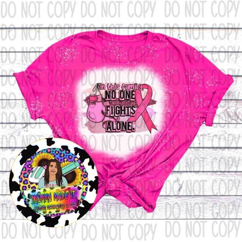 Puede incluir: Camiseta rosa con un dise&ntilde;o de salpicaduras blancas y el texto "En esta familia, nadie lucha solo!" con una cinta rosa y un guante de boxeo. Una pegatina de vaca en blanco y negro con un girasol y el texto "Mam&aacute; lo hizo. Calcoman&iacute;as y arte personalizados de vinilo."