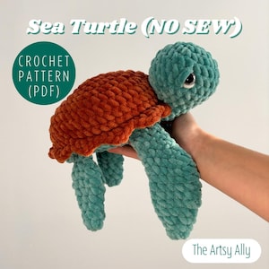May include: A crocheted sea turtle toy with a brown shell and teal body. The toy is made with a no-sew technique and is being held in a hand. The text "Sea Turtle (NO SEW)" and "CROCHET PATTERN (PDF)" is visible in the image.