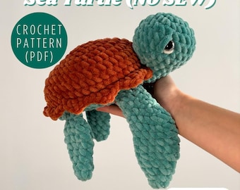 May include: A crocheted sea turtle toy with a brown shell and teal body. The toy is made with a no-sew technique and is being held in a hand. The text "Sea Turtle (NO SEW)" and "CROCHET PATTERN (PDF)" is visible in the image.