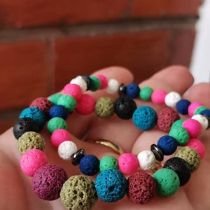 Pode incluir: Duas pulseiras de contas de rocha vulcânica coloridas com uma variedade de cores, incluindo rosa, verde, azul, preto, branco e marrom.