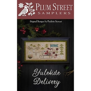 May include: A cross-stitch pattern sampler titled "Yuleside Delivery" featuring a reindeer pulling a sleigh with a figure in red delivering gifts. The sampler is framed in a dark wood frame with a green mat. The image is set against a dark wood background with greenery and red berries.