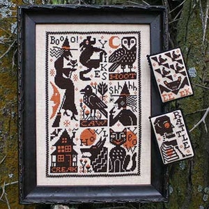 May include: A black and white cross-stitch pattern with a Halloween theme. The pattern features a witch, a cat, a wolf, a crow, an owl, a house, and the words "Boo!" "Hoot!" "Shhh!" "Caw!" "Howl!" "Creak!" and "Rattle!"