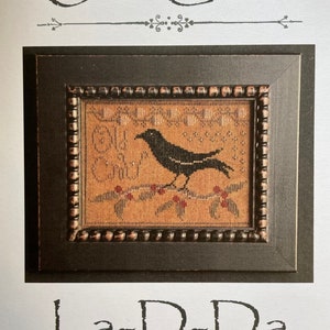 May include: A cross-stitch pattern featuring a black crow perched on a branch with red berries. The pattern is titled "Old Crow" and is from La-D-Da designs for counted thread.