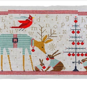 May include: A cross-stitch pillow featuring a red cardinal, a deer wearing pajamas, and two bunnies wearing pajamas, all standing in front of a Christmas tree with red ornaments. The alphabet is stitched above the scene.