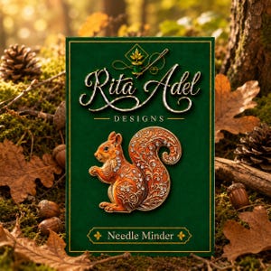 May include: A rectangular green display card featuring the text Rita Adel DESIGNS and Needle Minder. Centered on the card is a metallic orange squirrel-shaped needle minder decorated with intricate filigree patterns and embedded clear crystals.