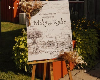 Puede incluir: Un caballete de madera exhibe un letrero de bienvenida de boda. El letrero presenta una ilustración en blanco y negro de un paisaje con un árbol, edificios y un faro. El texto dice "Welcome to the Wedding of Mike & Kylie" y "September 27 2024". Flores secas adornan el letrero.