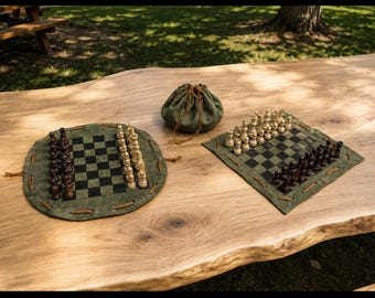 Könnte beinhalten: Zwei Schachspiele mit grünen Wildlederbrettern und Holzfiguren werden auf einem Holztisch präsentiert. Eines ist rund, das andere quadratisch. Zwischen ihnen liegt ein grüner Kordelzugbeutel. Die Schachfiguren sind hell und dunkel.