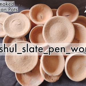 May include: A collection of small, smoked, terracotta Indian pots. The pots are round and have a slightly uneven surface. The pots are stacked on top of each other and are arranged in a random pattern. The text "anshul_slate_pen_works" is visible in the image.