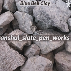 May include: Close-up of a pile of gray and blue slate rocks. The rocks are rough and textured. The text "Blue Bell Clay" and "anshul_slate_pen_works" is visible in the image.