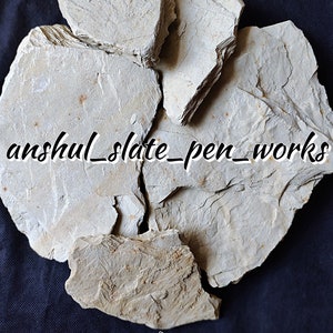 May include: Raw Multani Mitti, a type of clay, in its natural form. The clay is broken into several pieces and has a light brown color. The image includes the text "anshul_slate_pen_works".