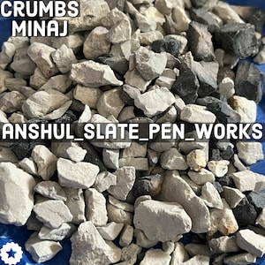 May include: A close-up image of a pile of small, grey and black slate rock pieces. The text "CRUMBS MINAJ ANSHUL SLATE PEN WORKS" is visible in the image.