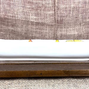 Puede incluir: Una fuente de cer&aacute;mica blanca con forma alargada, similar a un barco. Se encuentra sobre una bandeja de madera oscura. El fondo es una tela texturizada de color neutro. Ideal para servir.