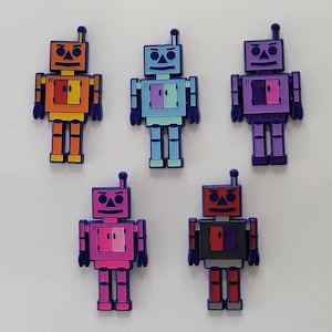Puede incluir: Cinco pequeñas figuras de robots de diferentes colores. Los robots tienen todos el mismo diseño, con un cuerpo cuadrado, una cabeza redonda y dos brazos. Los robots son naranja, azul, morado, rosa y rojo.