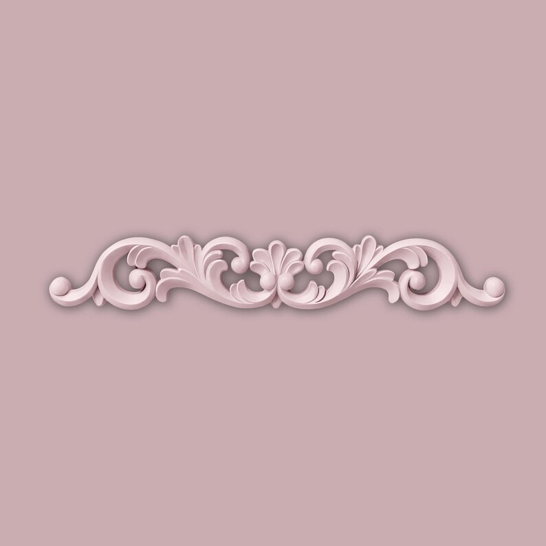 May include: A pale pink decorative moulding featuring a symmetrical design of swirling leaves and scrolls. The moulding is set against a matching pink background, creating a seamless and elegant look. This decorative element is suitable for interior design projects.