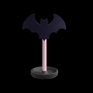 K&ouml;nnte beinhalten: Dekorative fledermausf&ouml;rmige Objekt mit einer dunkelblauen Silhouette. Die Fledermaus ist auf einem hellrosa Stiel montiert, der an einer dunkelgrauen, kreisf&ouml;rmigen Basis befestigt ist. Schwarzer Hintergrund.