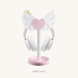May include: White headphone stand with a pink heart and wings. The base is pink and has a ribbed design. The stand is called "RIBBED BASE".