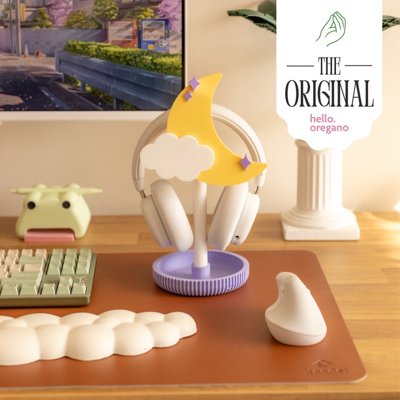 May include: A purple and white headphone stand with a yellow crescent moon and a white cloud. The stand is on a brown desk with a white cloud-shaped mousepad and a white mouse.