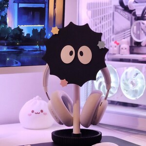 May include: A black headphone stand in the shape of a soot sprite, with white eyes and star decorations. It holds white headphones. A white mouse and a dumpling-shaped lamp are also visible.