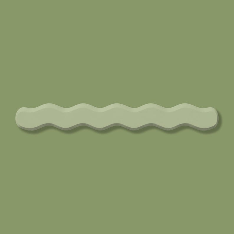 May include: A sage green, wavy-shaped hair clip. The clip has a matte finish and a subtle shadow, creating a three-dimensional effect. The background is a matching sage green.