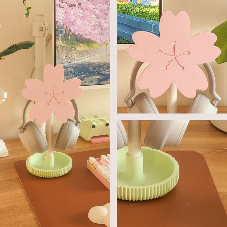 May include: A light green and pink headset stand with a cherry blossom design. The stand has two hooks for headphones and a base with a decorative pattern.