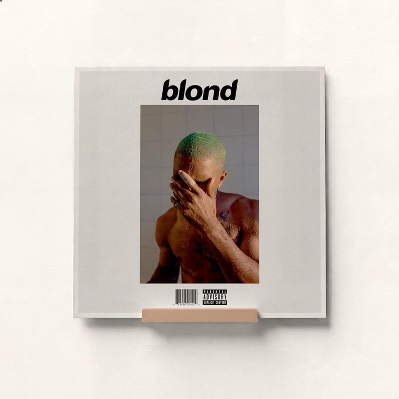 May include: A framed print featuring the album cover for "Blond." The image shows a person with green hair covering their face. The word "blond" is printed in black at the top. A parental advisory sticker is visible.