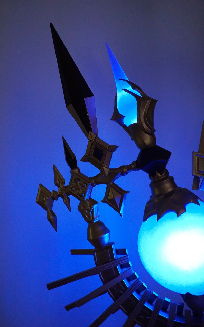 May include: A decorative lamp with a blue light orb and intricate metalwork. The lamp features a black and gold design with a pointed, angular shape.
