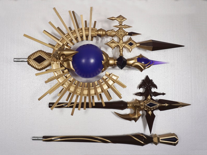 May include: Three decorative golden staffs with purple and black accents. The staffs feature a sunburst design, a sphere, and a pointed tip.