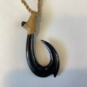 May include: A black fish hook pendant necklace with a brown braided cord.