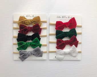 May include: Set of ten velvet hair bows in various colours, including red, green, gold, and grey. The bows are attached to nude elastic headbands. The image includes the text "Lottie Belles Boutique Vancouver, Canada www.lottiesbowtique.etsy.com"