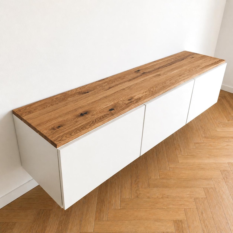 May include: A wall-mounted cabinet featuring a long, rectangular natural wood top with visible grain and knots, paired with three smooth, matte white cabinet doors positioned horizontally beneath the wooden surface.