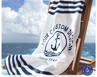 May include: White beach towel with navy blue stripes and a custom anchor design. The towel is draped over a wooden beach chair. Text on the towel reads "YOUR CUSTOM DESIGN" and "YOUR TEXT". The towel is personalized.