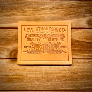 May include: A brown leather patch with the text "Levi Strauss & Co. San Francisco. Cal." and "Original riveted quality clothing." The patch also features a trade mark with two horses pulling a wagon, the text "Patented in U.S." and "May 20 1873."