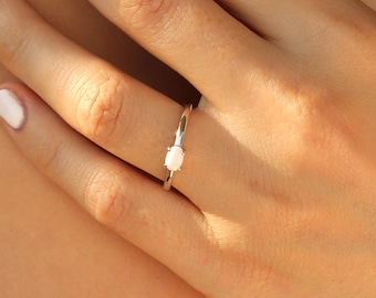 May include: A silver ring with a single, round, white gemstone set in the center.