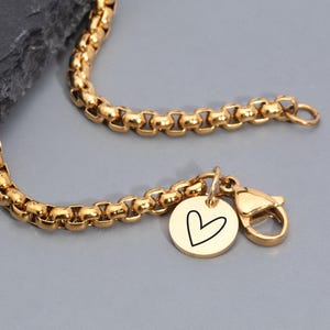 May include: A gold-toned rolo chain necklace featuring a small circular pendant engraved with a black heart outline. The text on the image reads: Waterproof, Hypoallergenic, Free Gift Box, Ships in 1-2 Days, Initials, coordinates, or icons available.