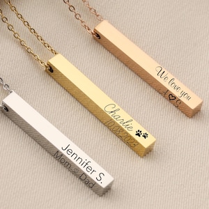 May include: Three gold bar necklaces with personalized engravings. The necklaces are silver, gold, and rose gold. The engravings read "We love you", "Charlie 10.08.2022", and "Jennifer S. Mom & Dad".