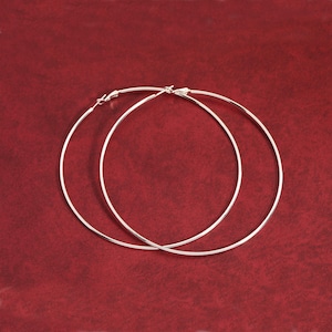 May include: A pair of silver hoop earrings. The hoops are large and circular, and they are made of a thin metal.