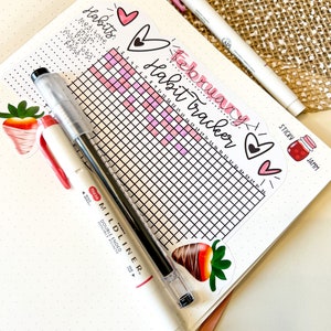 May include: A pink and white habit tracker for the month of February. The tracker has a grid with 28 squares, each representing a day of the month. The tracker is decorated with hearts and strawberries.