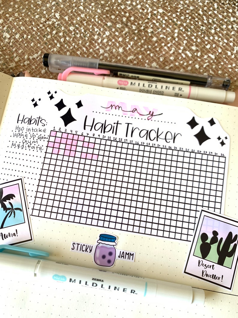 May include: A habit tracker for the month of May with a grid of 31 squares. The tracker is decorated with black diamond stickers and the words "Habit Tracker" are written in black cursive. The tracker is on a white background with a pink gradient at the top.