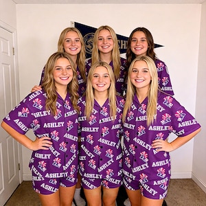 K&ouml;nnte beinhalten: Sechs Personen tragen passende lila Pyjama-Sets. Die Pyjamas haben ein sich wiederholendes Muster mit dem Namen "ASHLEY" und einer Grafik. Die Sets umfassen ein Hemd mit Kn&ouml;pfen und Shorts.