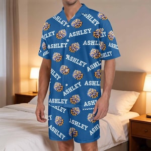 K&ouml;nnte beinhalten: Blaues Pyjama-Set mit dem Namen "ASHLEY" in Wei&szlig; und Gelb. Das Set besteht aus einem kurz&auml;rmeligen Hemd und Shorts aus leichtem Stoff. Dieses bequeme Set ist ideal zum Entspannen und Schlafen.