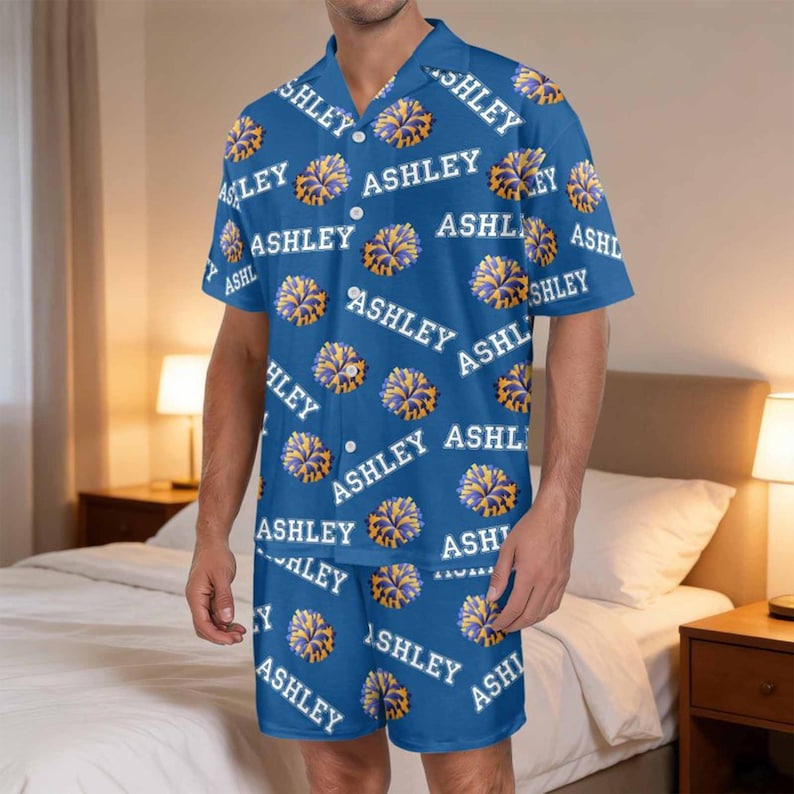 K&ouml;nnte beinhalten: Blaues Pyjama-Set mit dem Namen "ASHLEY" in Wei&szlig; und Gelb. Das Set besteht aus einem kurz&auml;rmeligen Hemd und Shorts aus leichtem Stoff. Dieses bequeme Set ist ideal zum Entspannen und Schlafen.