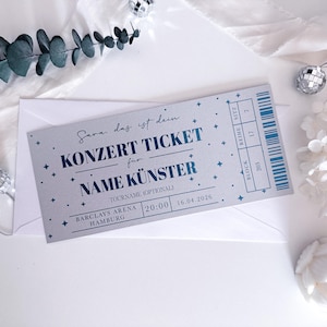 Puede incluir: Una entrada de concierto con texto azul y estrellas, dentro de un sobre blanco. La entrada dice "KONZERT TICKET" e incluye detalles del lugar, la fecha y la hora. Elementos decorativos incluyen bolas de discoteca y vegetaci&oacute;n.