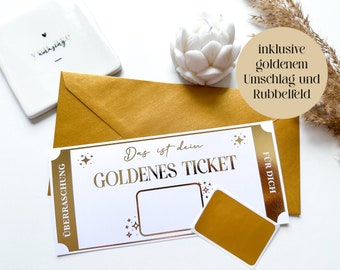 Może przedstawiać: Biały bilet z pozłacanymi literami, na którym widnieje napis "Das ist dein GOLDENES TICKET" i "ÜBERRASCHUNG", a po obu stronach znajduje się złota gwiazda. Bilet ma puste miejsce do wpisania tekstu i złotą naklejkę z napisem "FÜR DICH". Bilet leży na złotej kopercie z białym kwiatem i tabliczką z napisem "inklusive goldenem Umschlag und Rubbelfeld".