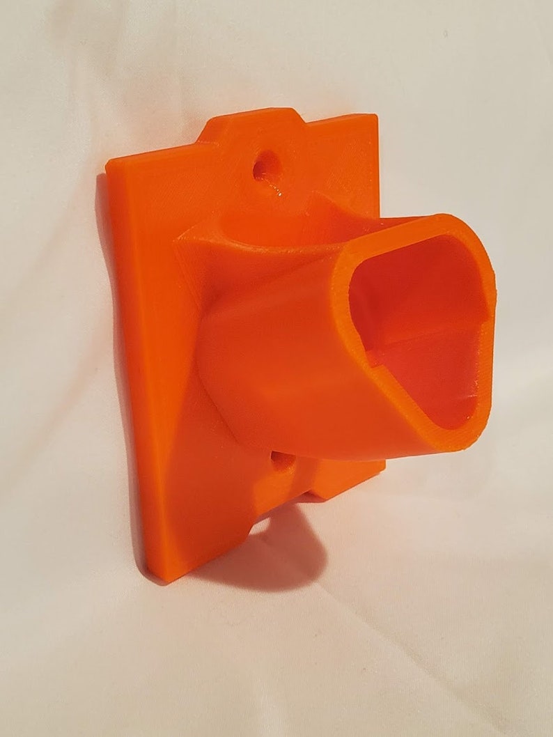Op de afbeelding: Oranje plastic wandbevestiging met een rechthoekige basis en een gebogen, open gleuf. De bevestiging heeft een gat voor een schroef of spijker.