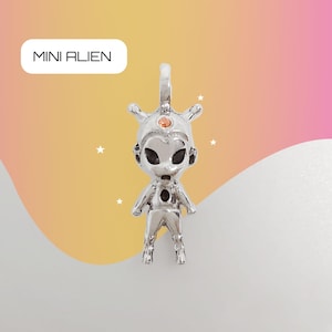 Puede incluir: Encanto de plata con un pequeño extraterrestre con un tercer ojo y una piedra preciosa de color cobre. El encanto está etiquetado como "MINI ALIEN".
