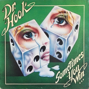 May include: A green album cover with the text "Dr. Hook" in white cursive lettering. Two dice with faces of women are depicted, one with a tear rolling down its cheek. The text "Sometimes You Win..." is written in white cursive lettering.