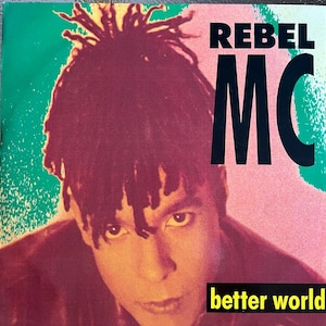 May include: Album cover for Rebel MC's "Better World." The image features a close-up of a person with dreadlocks, set against a backdrop of green, pink, and red hues. The text "REBEL MC" is prominently displayed, with "better world" at the bottom.