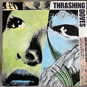 Puede incluir: Portada de álbum con un diseño de rostro dividido en tonos verdes y azules. El texto "THRASHING DOVES" está en la parte superior. La obra de arte tiene un estilo pop art con texto japonés en el lado derecho.